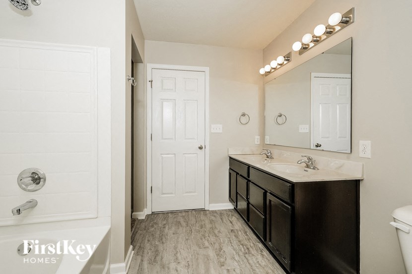 A bathroom with a white door and a black vanity.