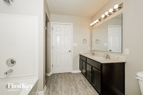 A bathroom with a white door and a black vanity.