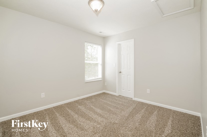 A carpeted room with a door and a window.