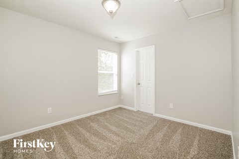 A carpeted room with a door and a window.