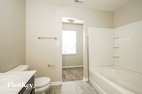 A white bathroom with a tub, toilet and sink.