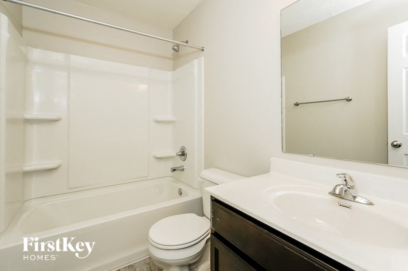 A white toilet sits in a bathroom with a white tub and sink.