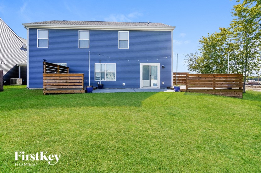 A blue house with a white door and windows is surrounded by a green lawn.
