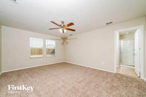 A spacious room with a ceiling fan and carpeted floor.