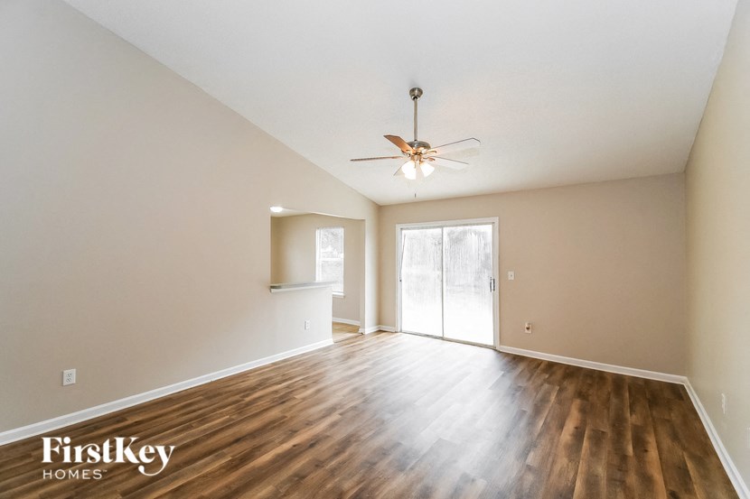 the spacious living room with hardwood flooring and a ceiling fan
