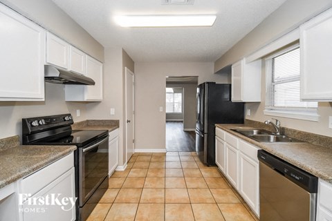 a kitchen with white cabinets and a black refrigerator and a sink
