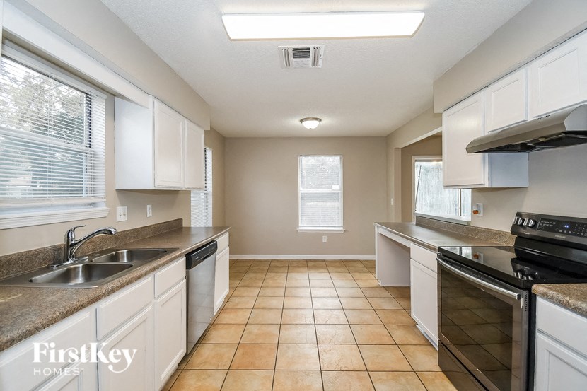 a kitchen with white cabinets and a stove and a sink