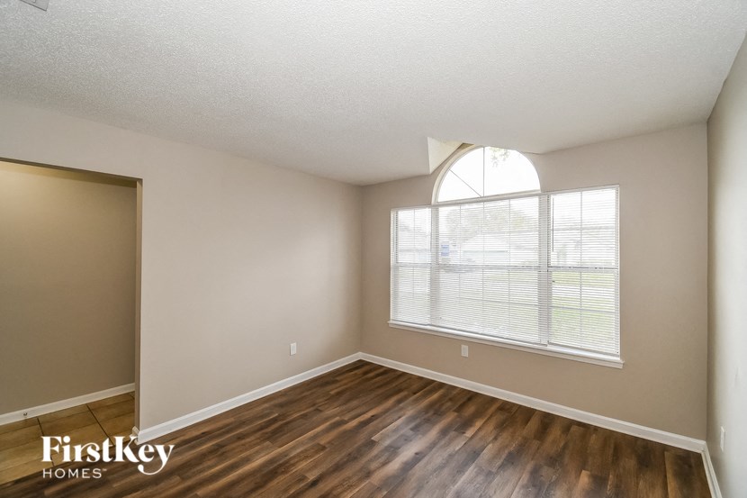the spacious living room with hardwood flooring and a large window