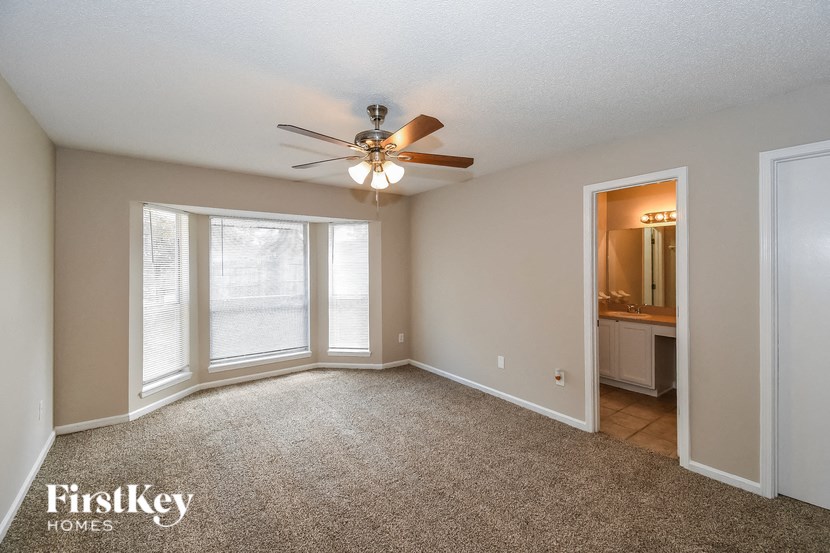 an empty living room with a ceiling fan and a window