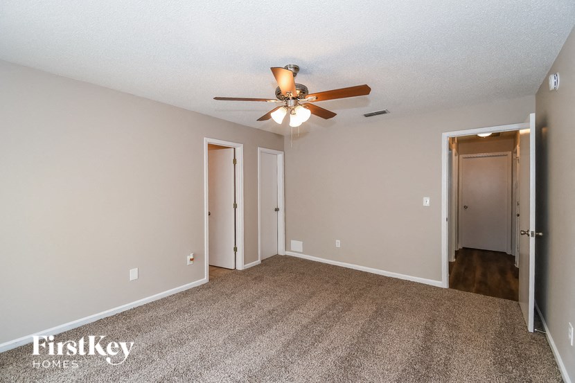 the spacious living room with carpeting and a ceiling fan