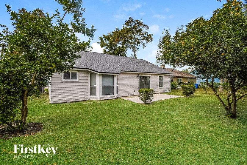 a small gray house with a yard and trees