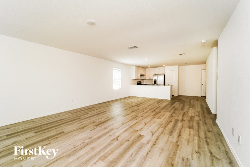 the living room and kitchen of an empty house with wood floors