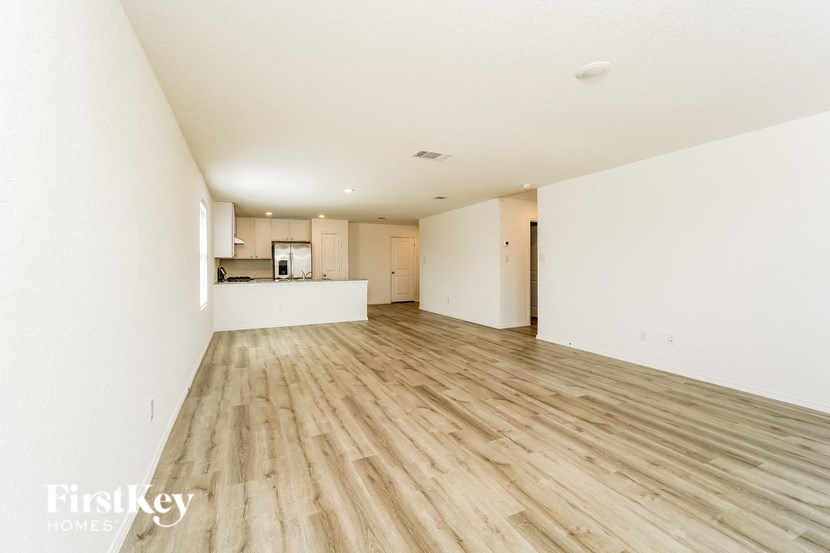 an empty living room and kitchen with wood floors and white walls