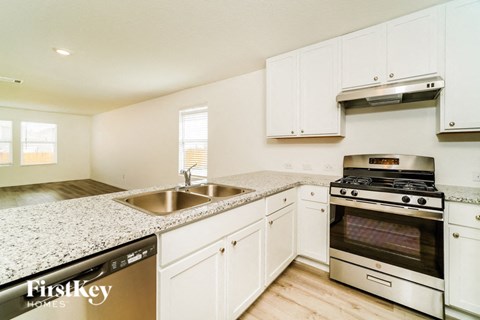 a kitchen with white cabinets and granite counter tops and stainless steel appliances
