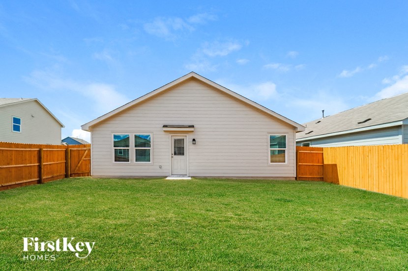 a backyard with a white house and a wooden fence