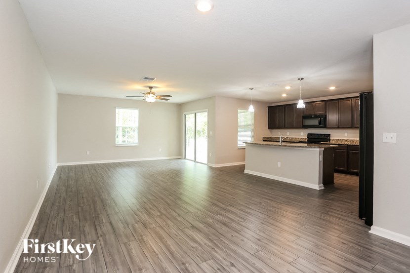 an empty living room and kitchen with wood flooring