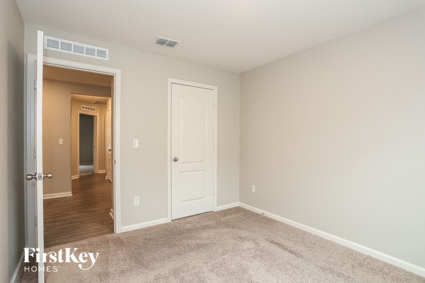a bedroom with a carpeted floor and a door to a hallway