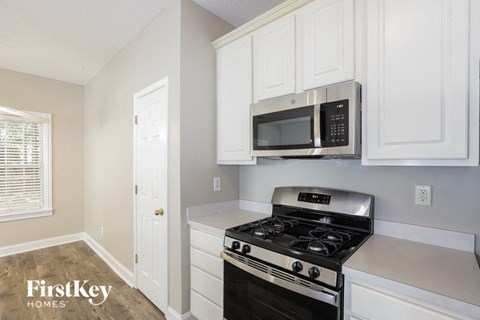 a kitchen with white cabinets and a stove and a microwave