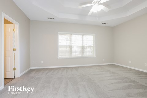 the living room of a new home with carpet and a ceiling fan