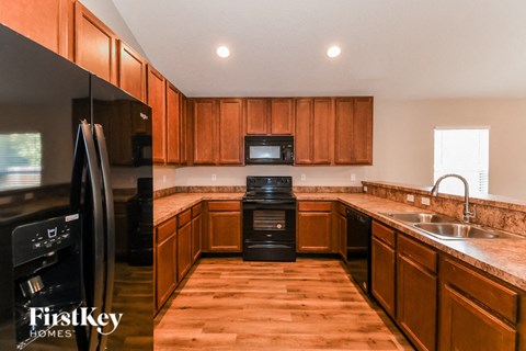 A kitchen with wooden cabinets and a black fridge.