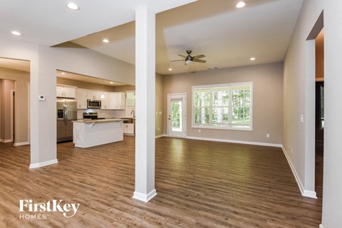 A spacious kitchen and living room with wooden floors and white walls.