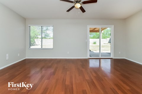 an empty living room with wood floors and a ceiling fan