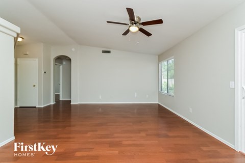an empty living room with wood floors and a ceiling fan