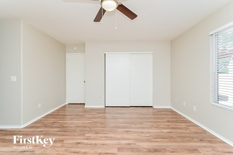 the spacious living room with wood flooring and a ceiling fan