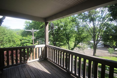 a porch with a view of trees and a street