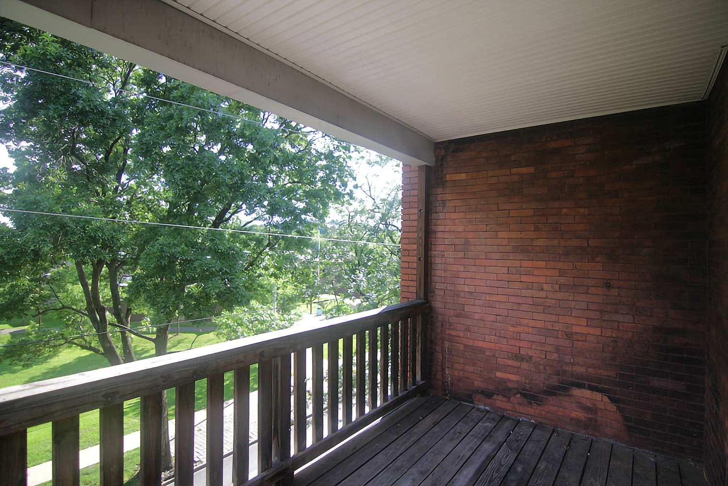 a porch with a brick wall and a wooden deck