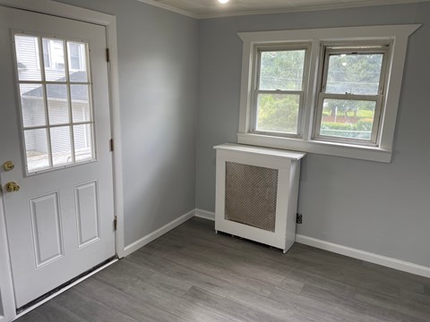 A room with a white door, a window with a white frame, and a window air conditioner unit.