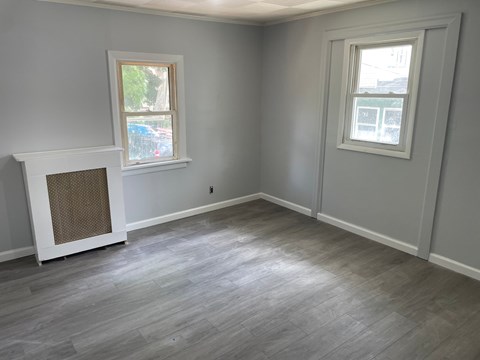 A room with a fireplace and two windows.
