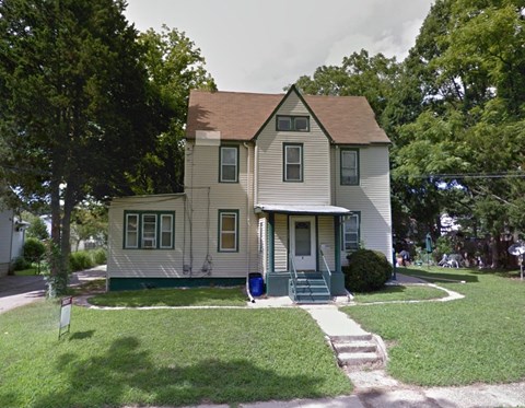 A two-story house with a green door and a small porch.