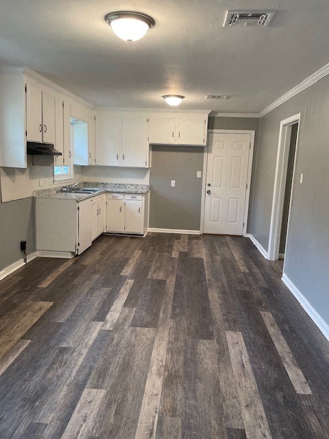 an empty kitchen with wood floors and white cabinets
