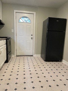 a kitchen with a black refrigerator and a door