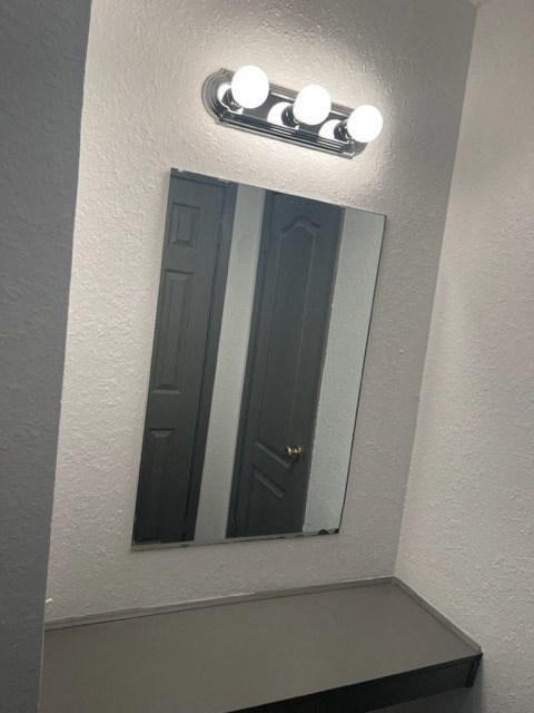 a bathroom with a mirror and a light on the wall