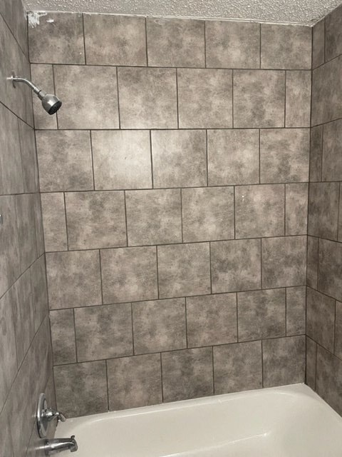 a bathroom with a shower and a tiled wall