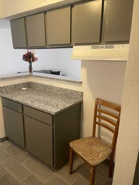 a small kitchen with a counter and a chair