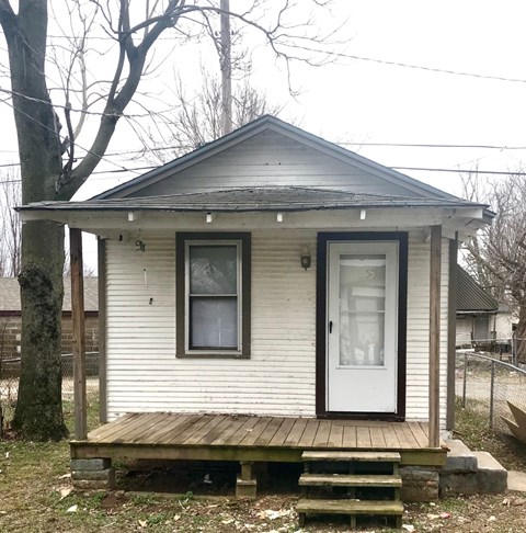 A small white house with a brown door and a porch.