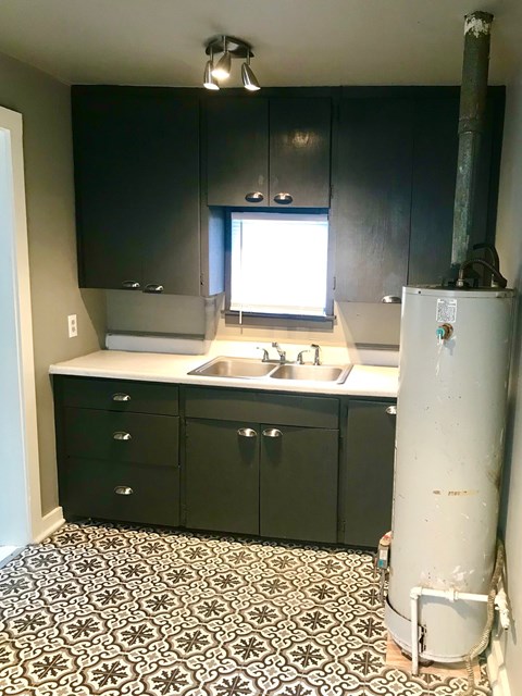 A kitchen with black cabinets and a white refrigerator.