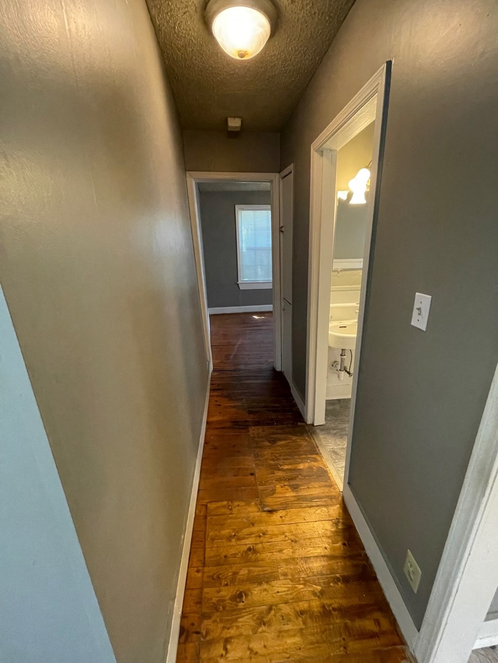 a hallway with a hard wood floor and a door to a bathroom