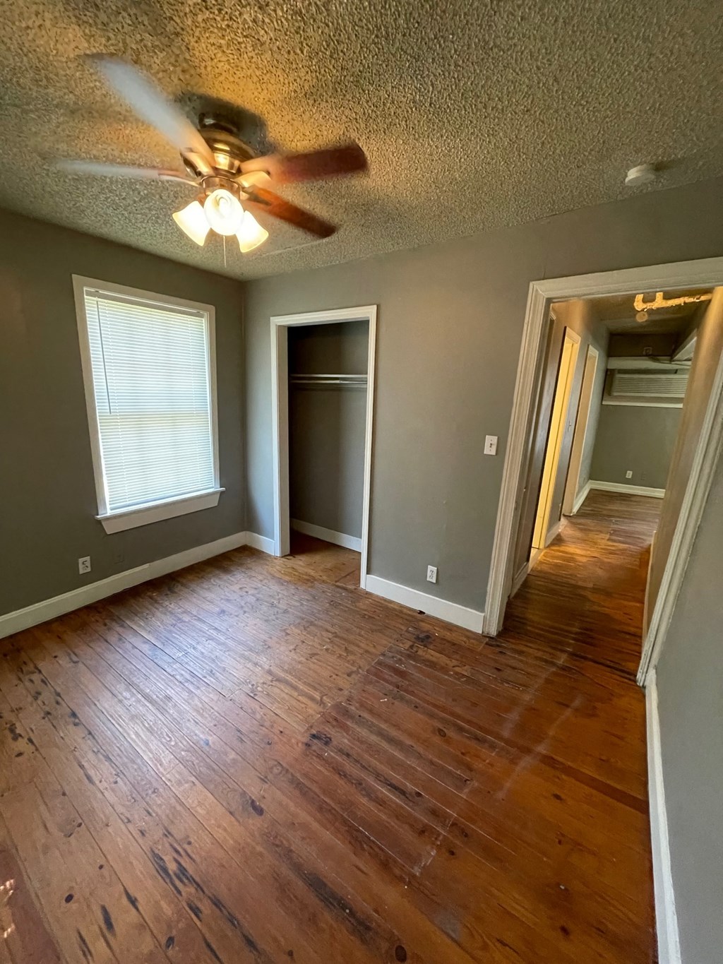 a empty living room with a ceiling fan and wood floors