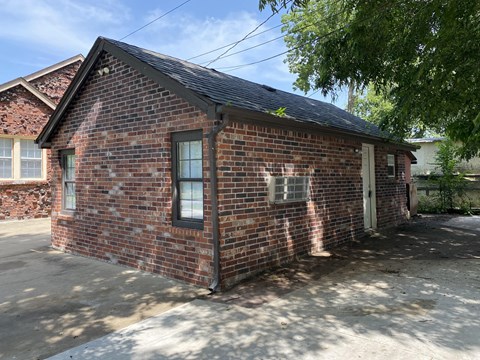 A small brick house with a white door and windows.