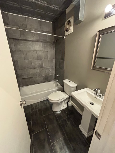 A bathroom with a toilet, sink, and tub.