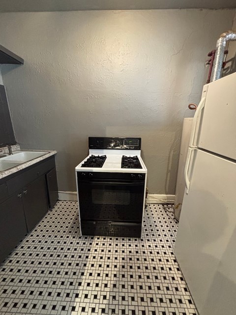 A black and white oven in a kitchen with a white tiled floor.