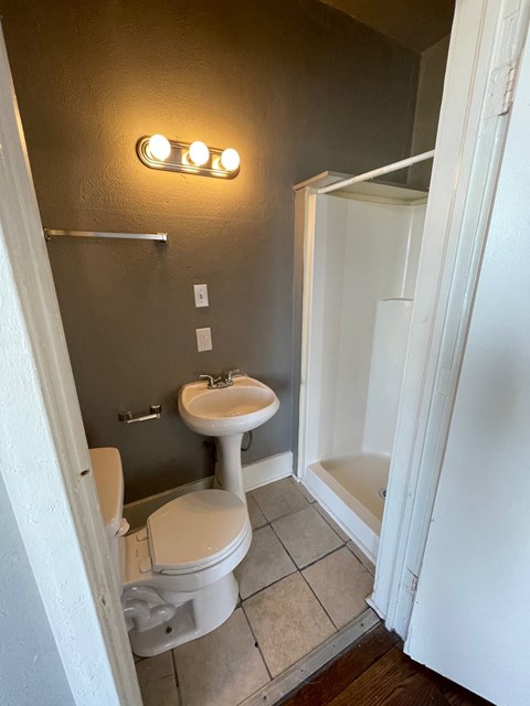 A bathroom with a toilet, sink, and shower.