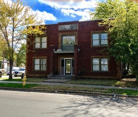 A red brick building with a yellow fire hydrant in front of it.