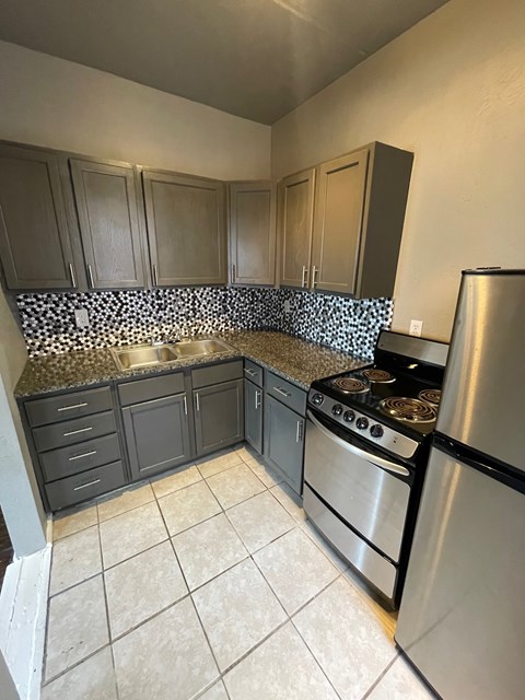 A kitchen with a stove top oven and a refrigerator.