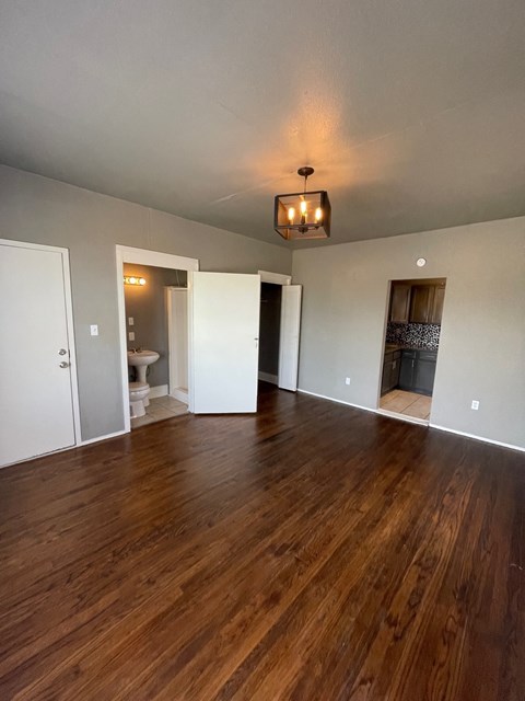 A room with wooden floors and a chandelier hanging from the ceiling.