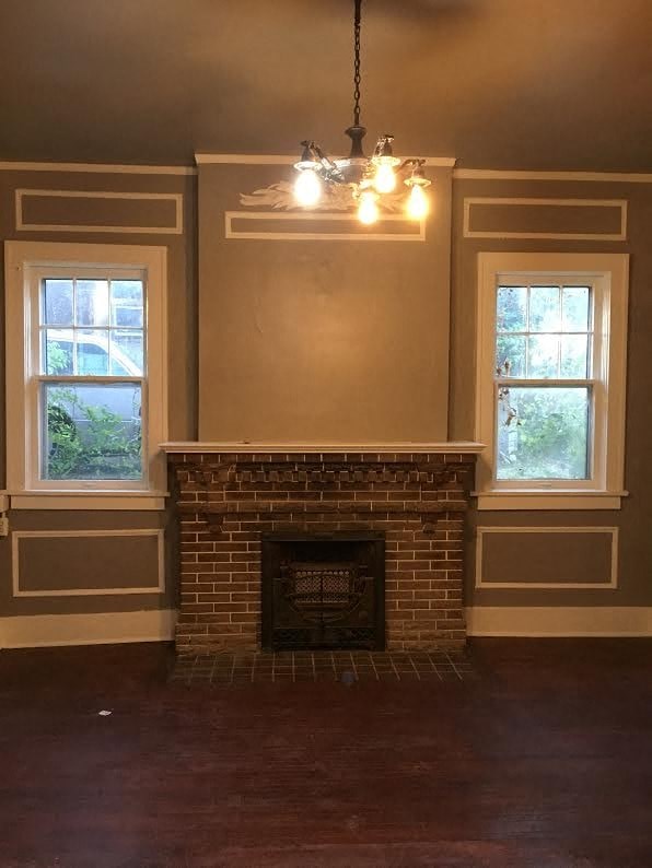 a living room with a brick fireplace and a chandelier